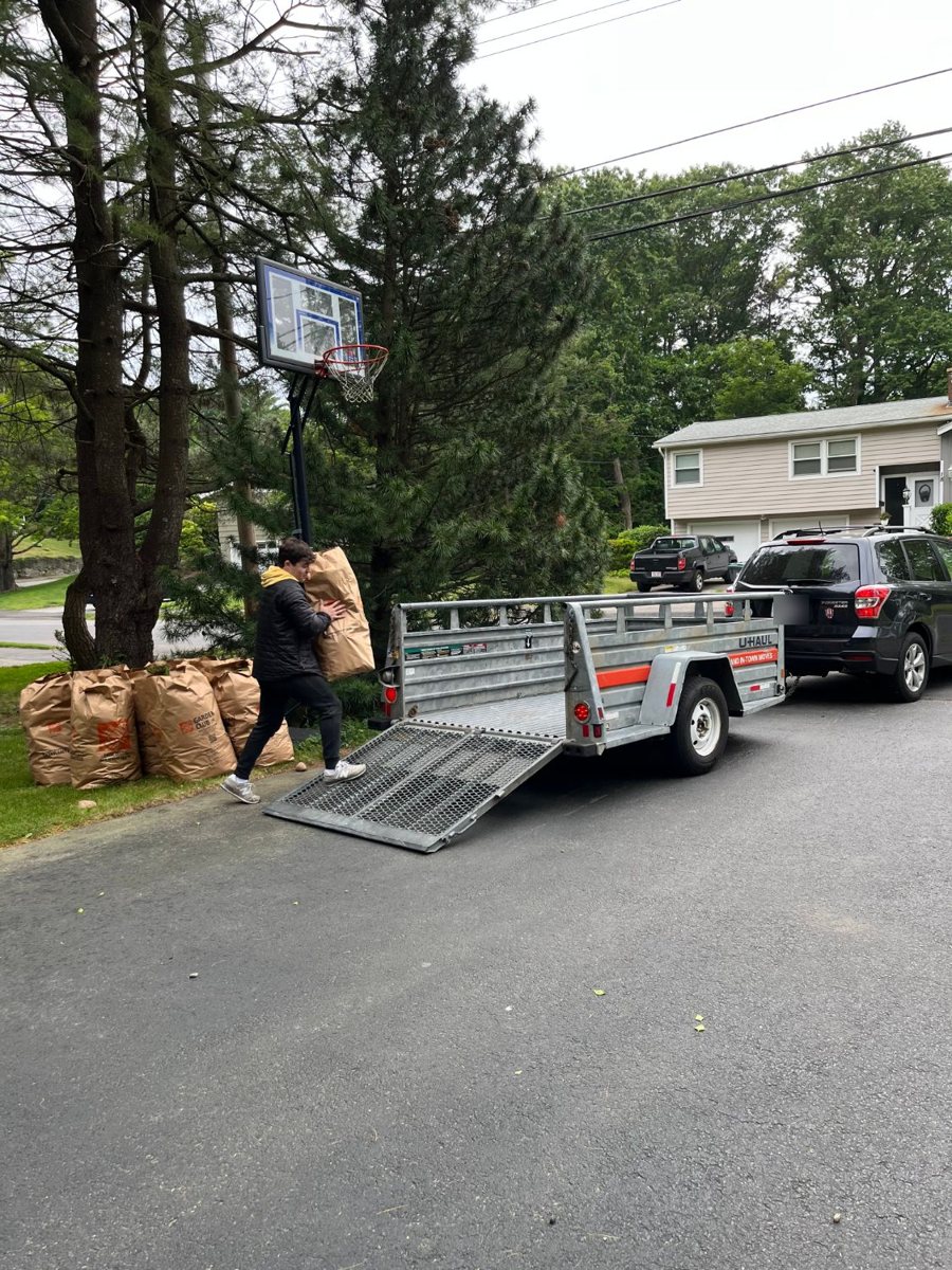 Noah loading yard waste bags onto a trailer